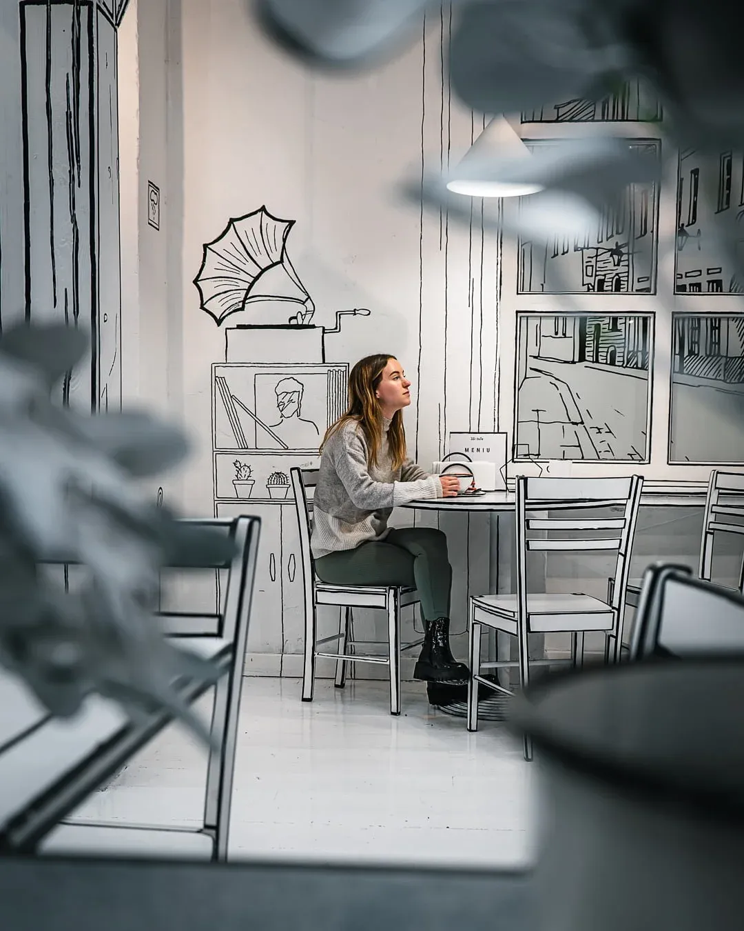 Woman sitting in 2d sketch illusion cafe in Vilnius