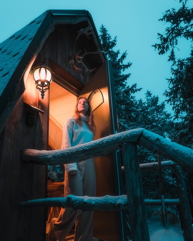 woman standing in doorway of igloo hotel at syote igloo, lapland