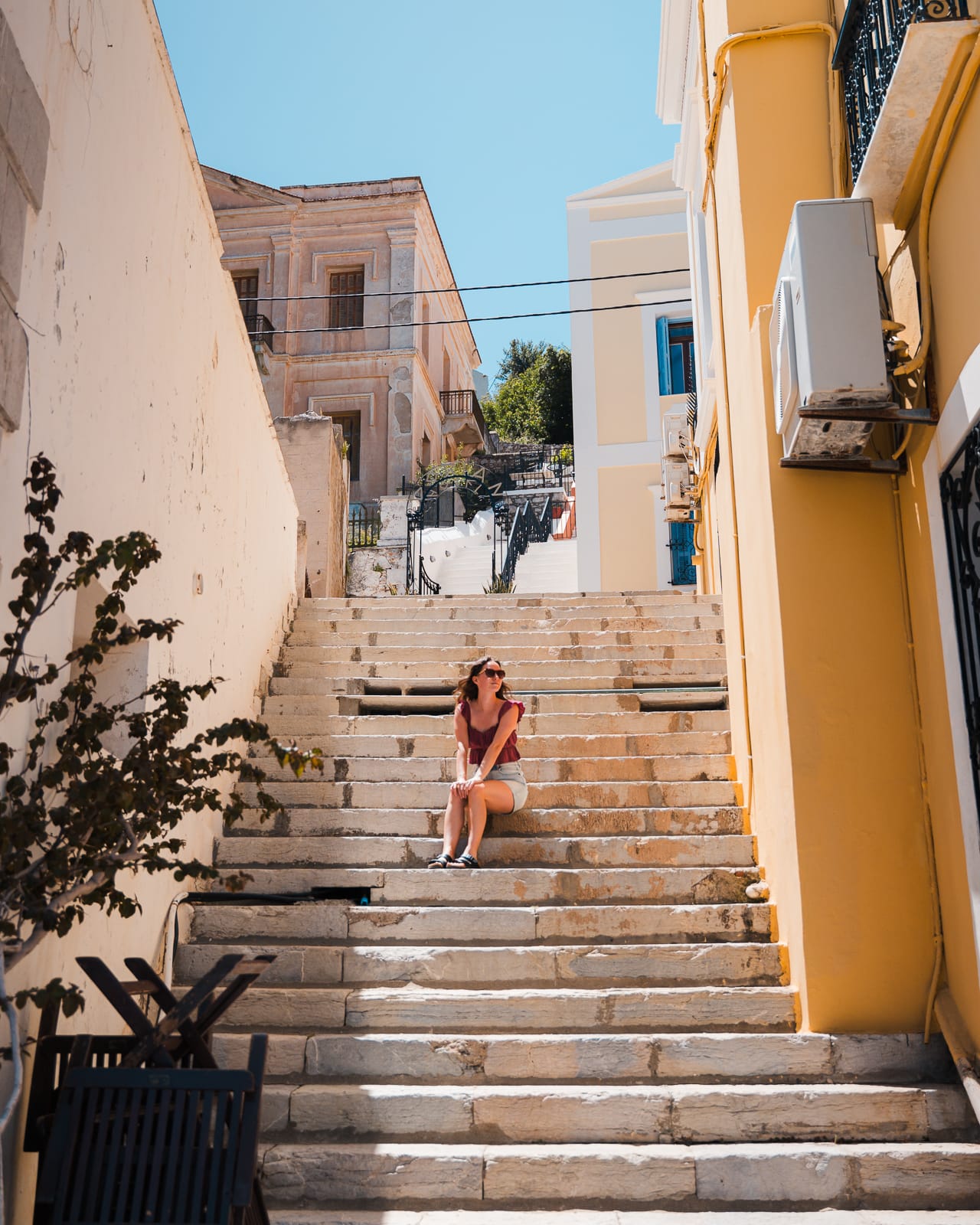 woman sitting on steps at symi island, greece