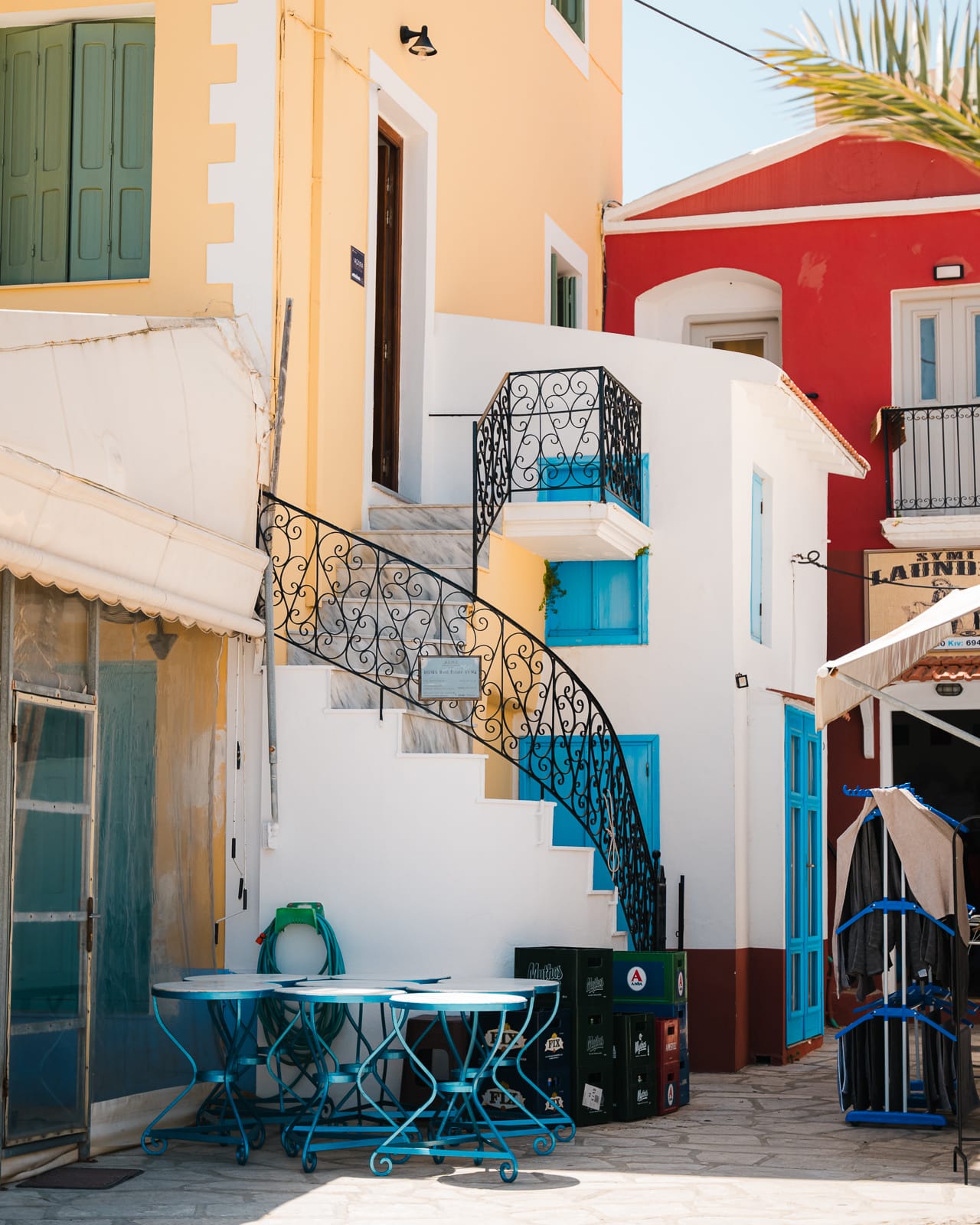 spiral staircase and yellow and red buildings with blue windows in symi island, greece