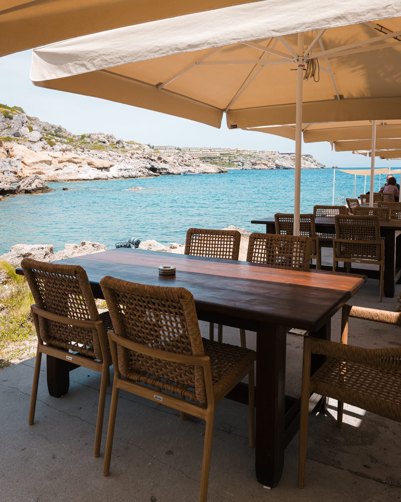 rattan chairs and wooden tables with sea in background at kalithea springs, rhodes