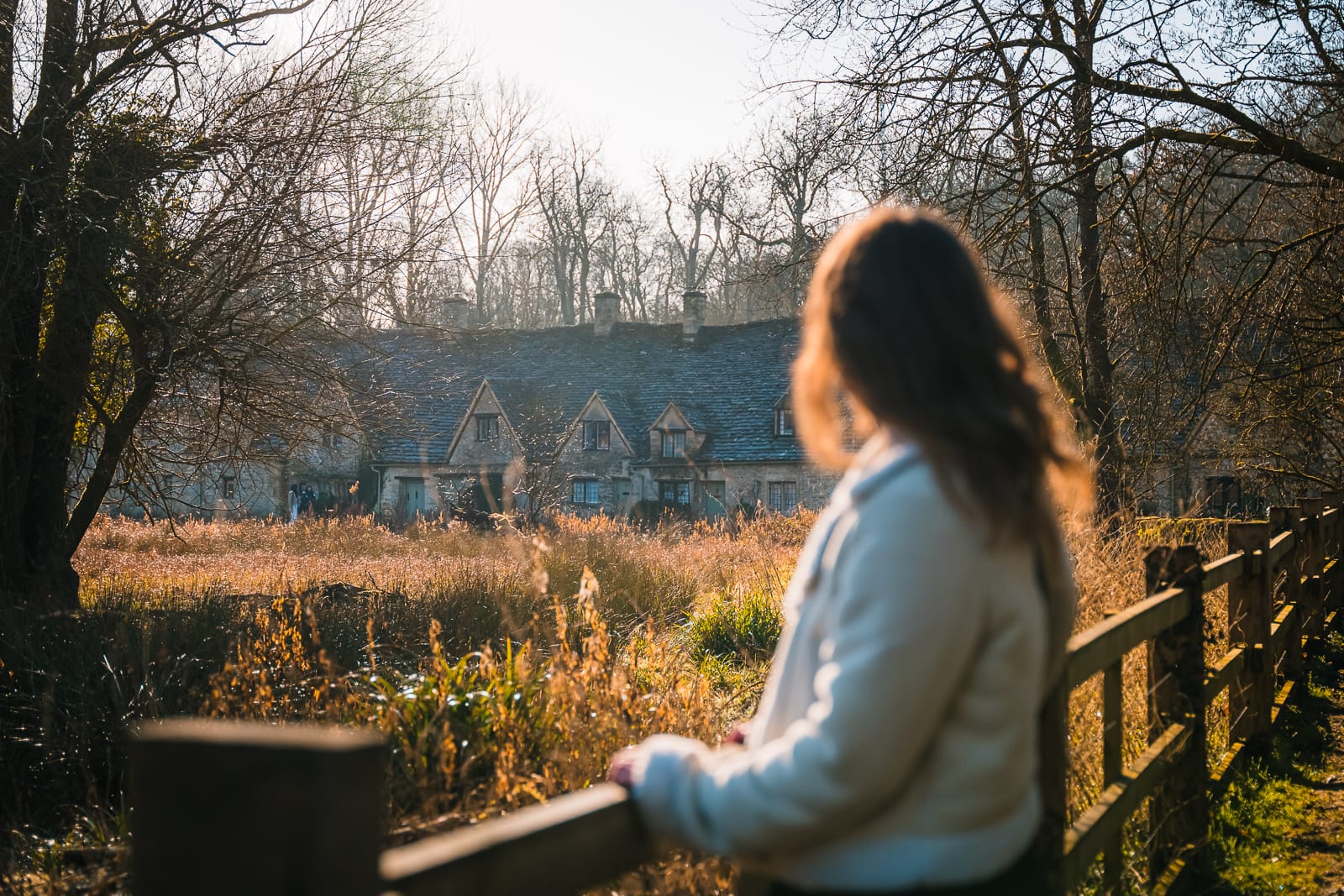 woman standing in woods overlooking arlington row, bibury