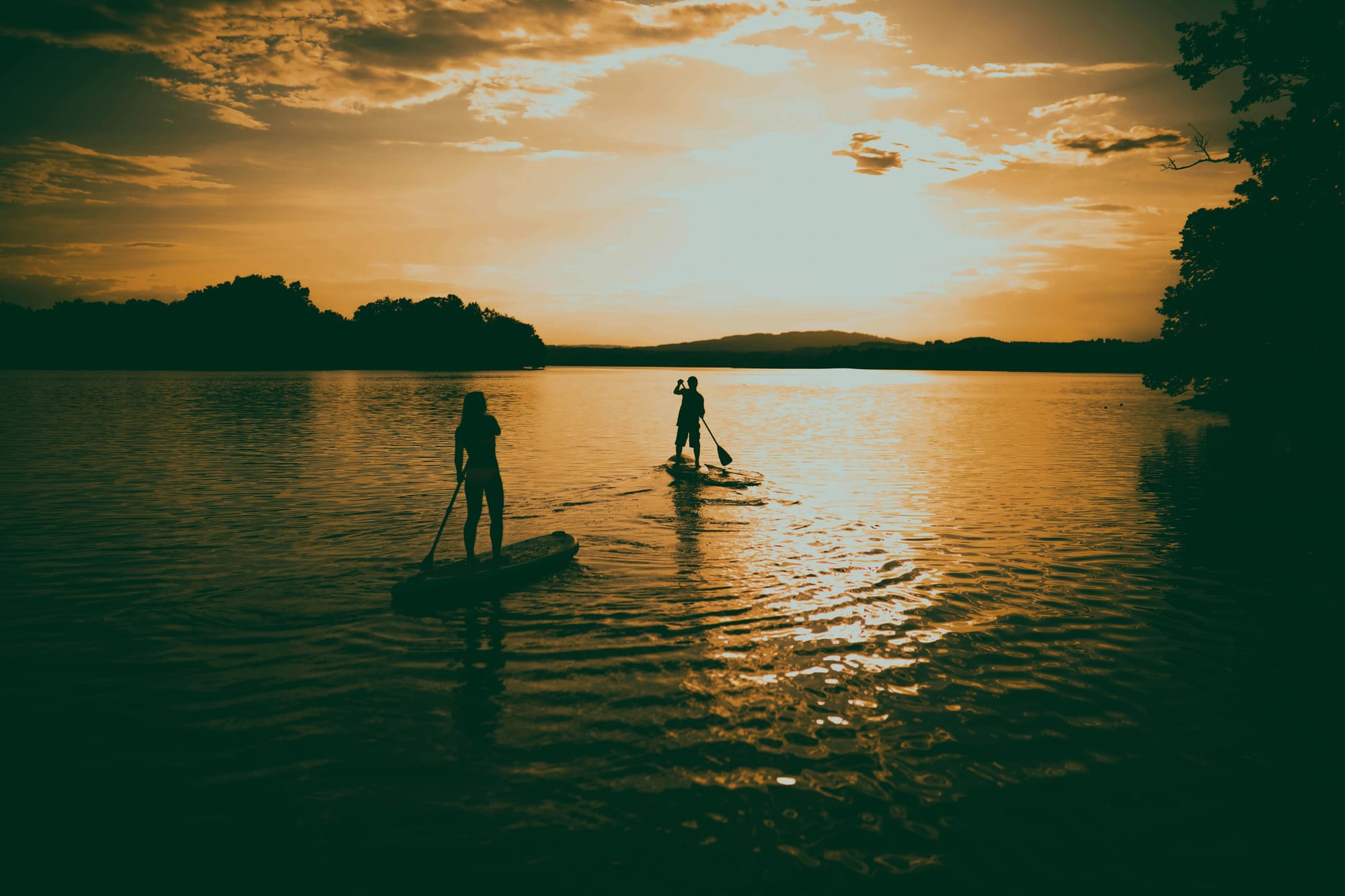 two people paddleboarding at sunset