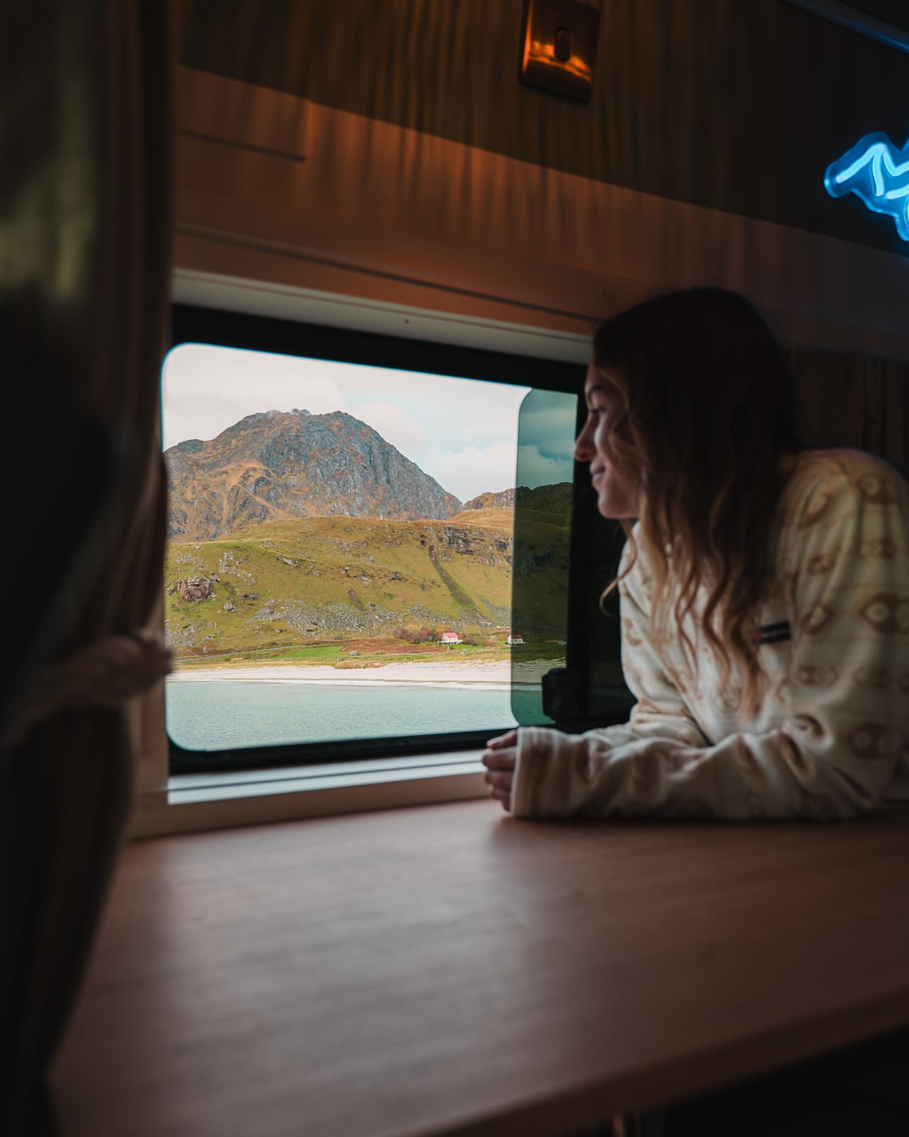 woman looking out of campervan window onto Haukland Beach, Norway
