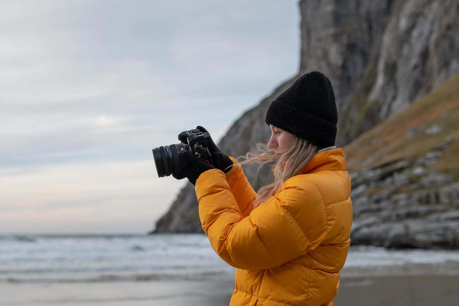 woman standing on beach with camera in hand