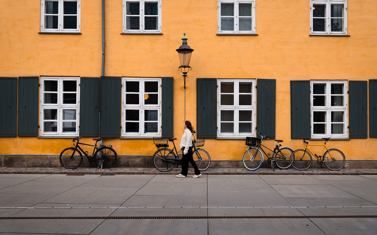 woman walking along pavement infront of yellow building in Copenhagen
