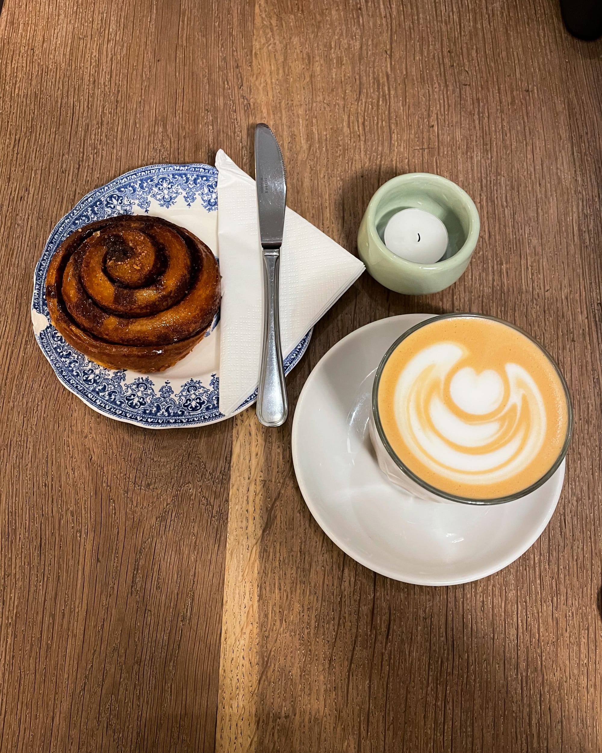 latte art and cinnamon bun on a table