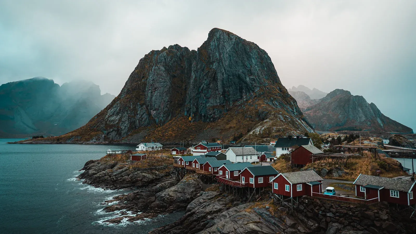 red rorbu cabins with mountain backdrop in lofoten, norway