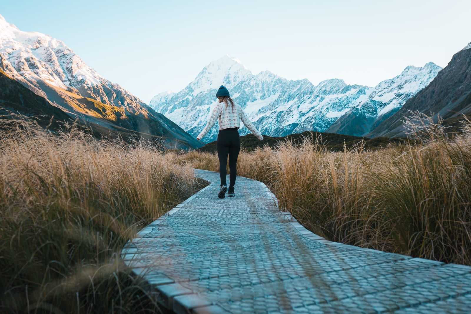 woman walking on wooden boardwalk on the hooker valley trail, mt cook national park