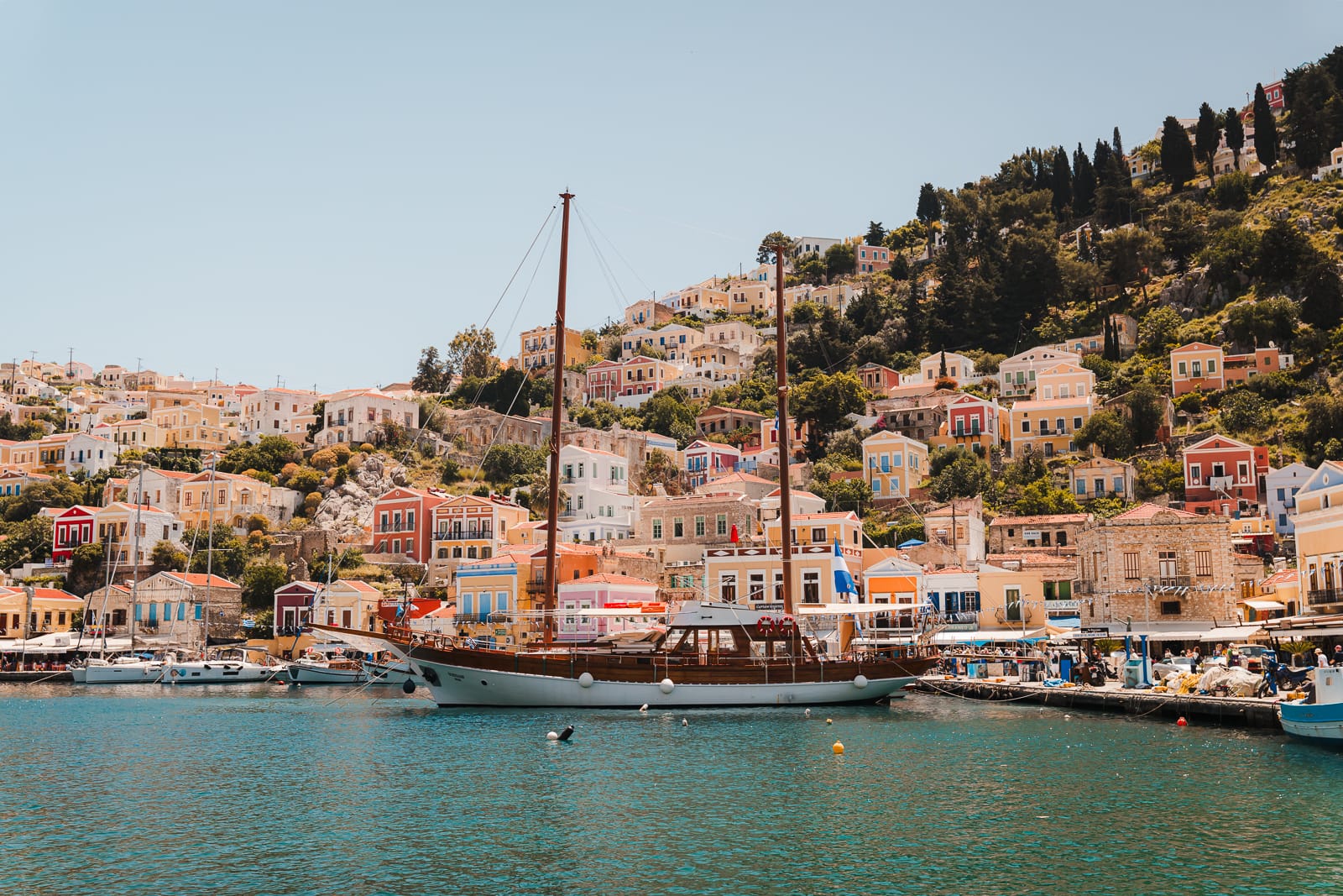 colourful buildings, boat and turqoise water at Symi Island, Greece
