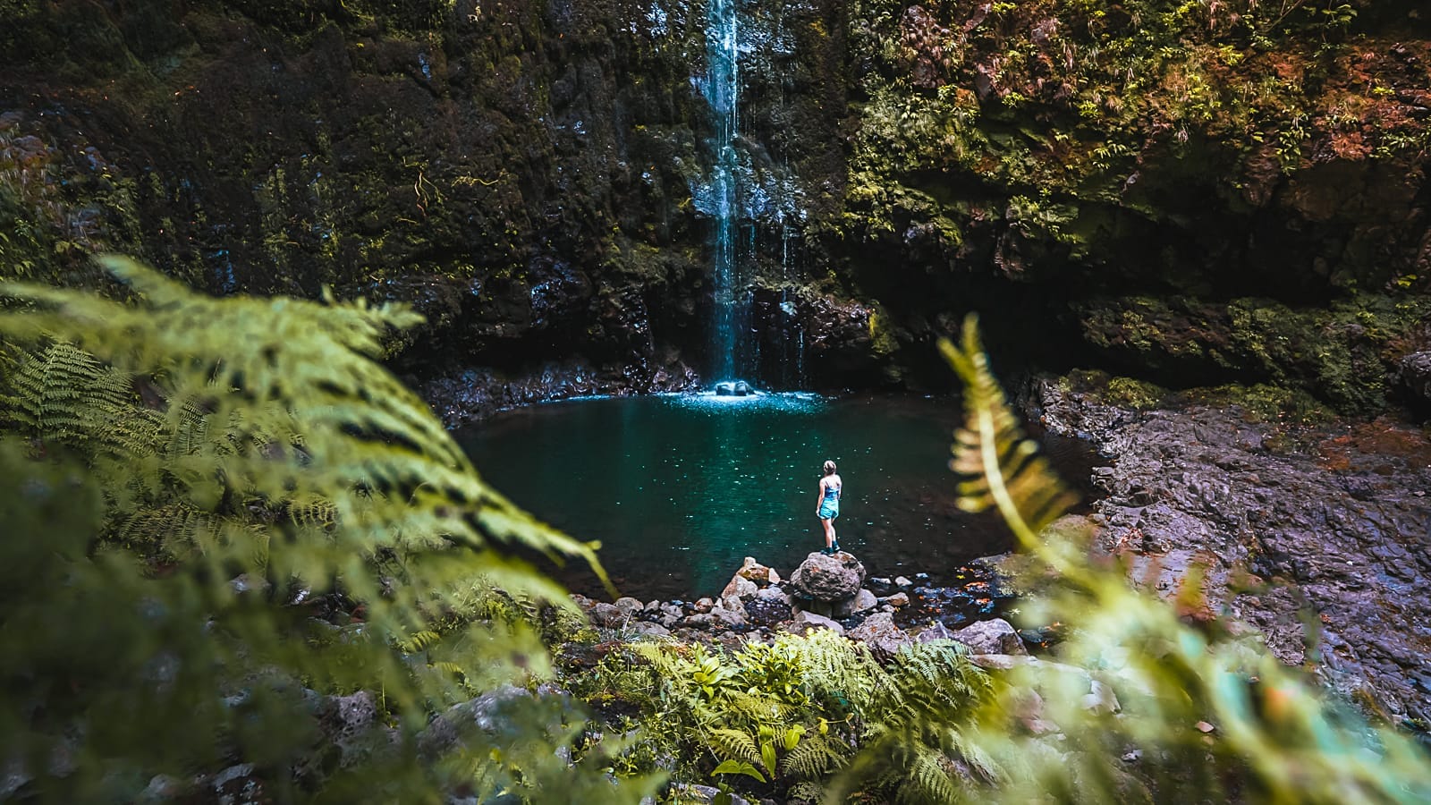 Woman standing at the base of Caldeirão Verde waterfall in Madeira